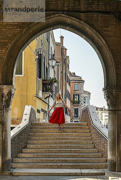 Junge Frau mit rotem Rock geht durch Torbogen  Mercato di Rialto  Venedig  Venetien  Italien  Europa