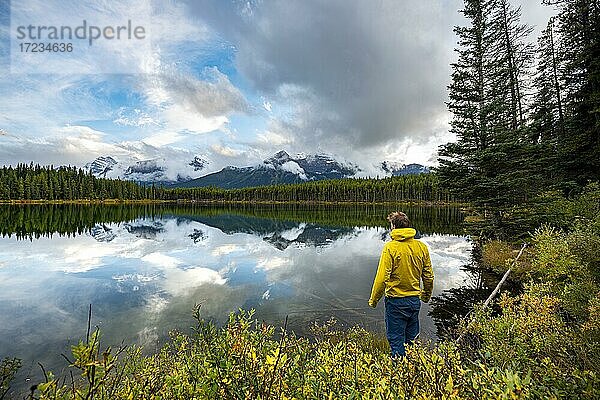Wanderer am Seeufer blickt auf Berge  herbstlicher Herbert Lake  Berge der Bow Range spiegeln sich im See  Banff National Park  kanadische Rocky Mountains  Alberta  Kanada  Nordamerika