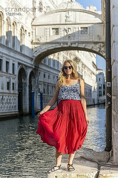 Junge Frau mit rotem Rock  Touristin am Kanal Rio di Palazzo  hinten Seufzerbrücke  Venedig  Venetien  Italien  Europa