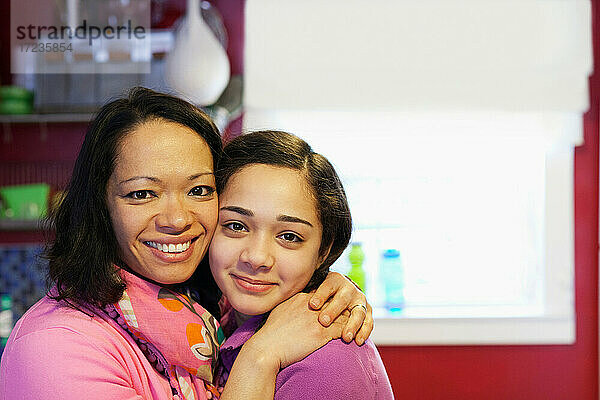 Porträt einer Mutter  die ihre Tochter in der Küche umarmt