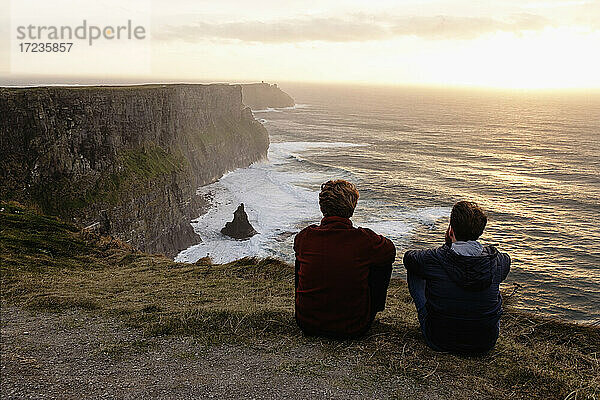 Zwei Männer sitzen auf den Cliffs of Moher  The Burren  County Clare  Irland