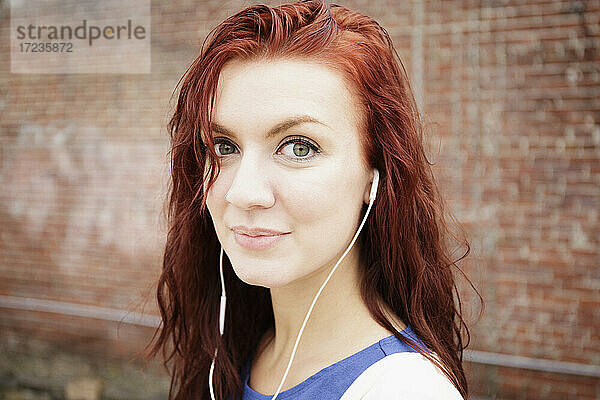 Porträt einer jungen Frau mit langen roten Haaren  die Kopfhörer trägt  Nahaufnahme