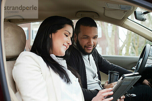 Junges Paar im Auto mit digitalem Tablet