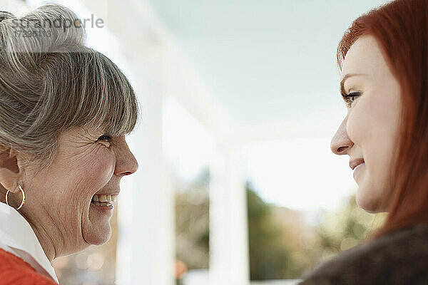 Nahaufnahme von älterer Frau und erwachsener Tochter lachend auf Veranda