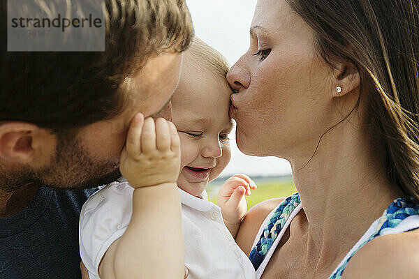 Nahaufnahme von Mitte Erwachsenen Eltern küssen Baby Tochter