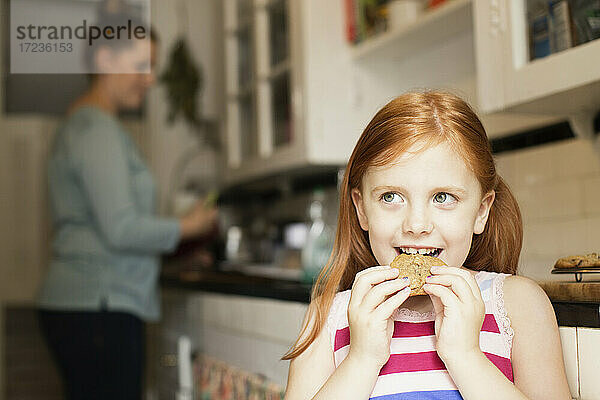 Mädchen isst Keks in der Küche