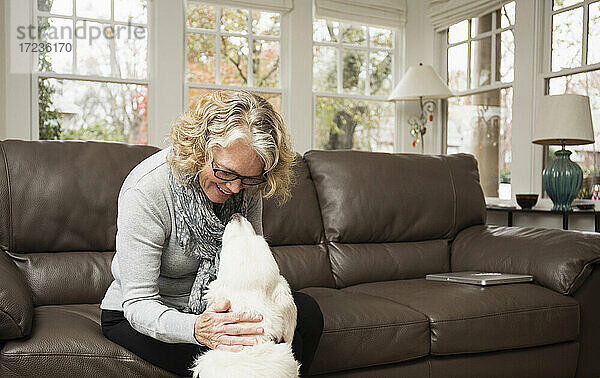 Ältere Frau mit Labradorhund im Wohnzimmer