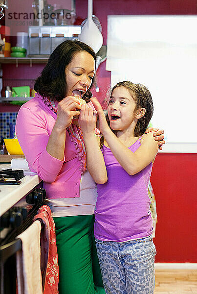 Tochter füttert Mutter Cracker in der Küche