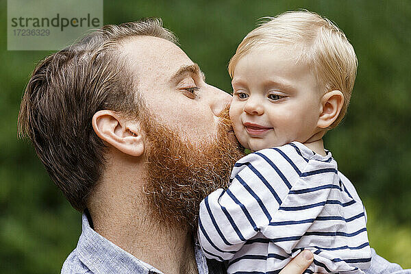 Porträt eines Vaters  der ein kleines Mädchen küsst  im Freien  lächelnd