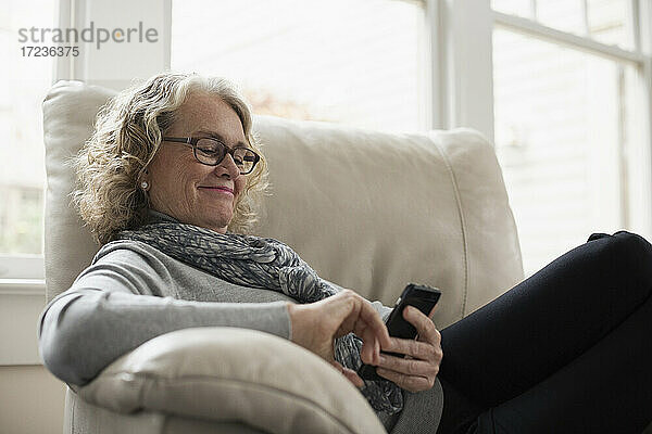 Ältere Frau entspannt auf Stuhl mit Handy