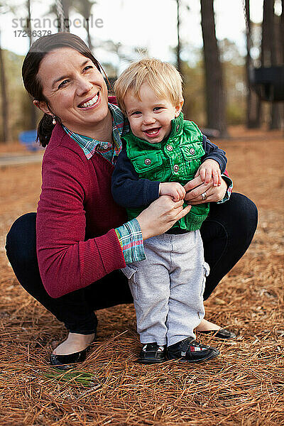 Lachende Mutter kitzelt Sohn im Park
