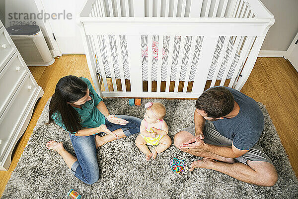 Hohe Winkel Ansicht der Mitte erwachsenen Paar spielt mit Baby-Tochter auf Kinderzimmer-Teppich