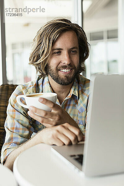 Mittlerer erwachsener Mann im Café  trinkt Kaffee  benutzt Laptop