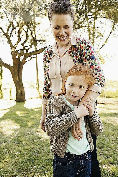 Porträt der mittleren erwachsenen Mutter mit Arm um Tochter im Park
