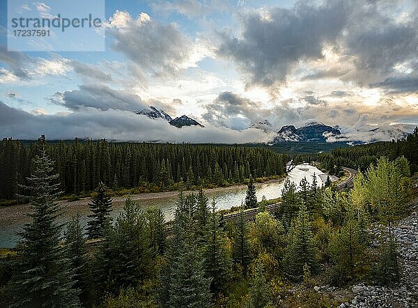 Wolkenverhangene Rocky Mountains bei Sonnenuntergang  Morant's Curve  bewaldetes Ufer am Bow River  Bow Valley  Banff-Nationalpark  Alberta  Kanada  Nordamerika
