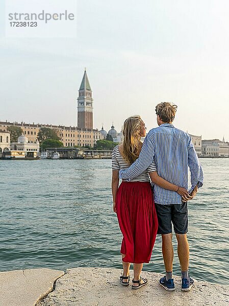 Junges Paar steht am Meer und genießt Blick auf Markusplatz mit Campanile di San Marco  Venedig  Venetien  Italien  Europa