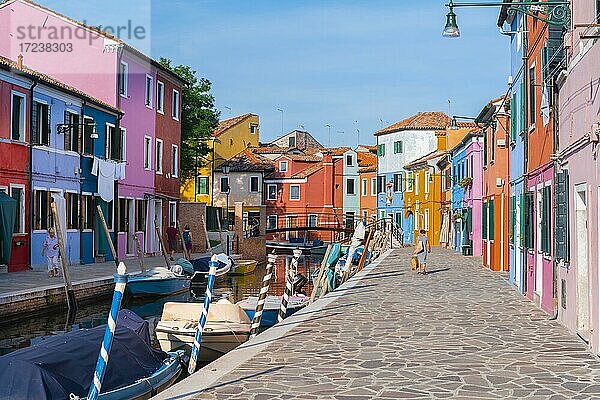 Frau geht an bunten Häusern vorbei  Kanal mit Booten und farbenprächtigen Häuserfassaden  Insel Burano  Venedig  Venetien  Italien  Europa