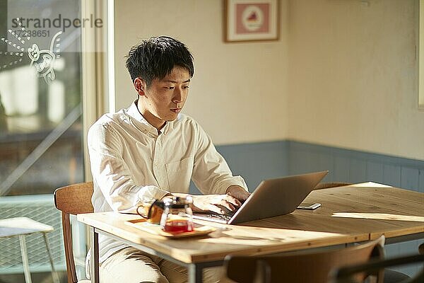 Junger japanischer Mann in einem Café