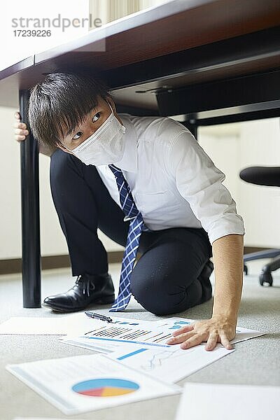 Japaner kniet während des Erdbebens unter dem Schreibtisch