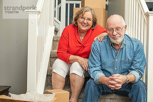 Älteres Paar ruht sich auf einer Treppe aus  umgeben von Umzugskartons