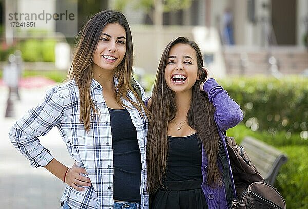 Porträt von zwei attraktiven multiethnischen Studentinnen  tragen Rucksack auf dem Schulcampus