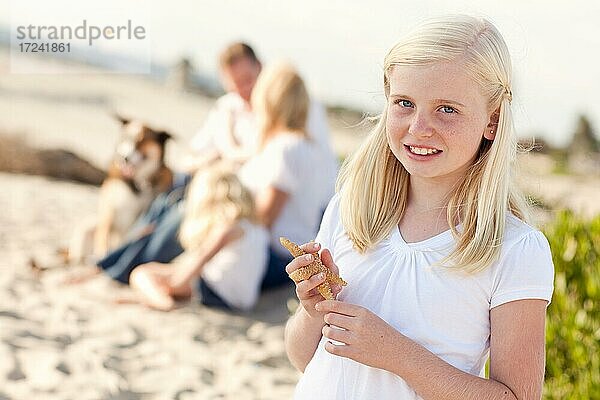 Niedliches kleines blondes Mädchen mit Seestern am Strand