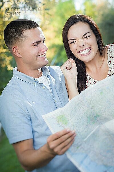 Glückliches gemischtrassiges Paar  das gemeinsam über eine Karte im Freien schaut