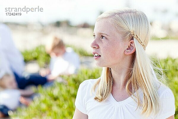 Niedliches kleines blondes Mädchen hat Spaß am Strand mit ihrer Familie