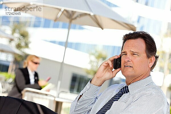 Selbstbewusster  gutaussehender Geschäftsmann lächelt  während er mit seinem Handy telefoniert
