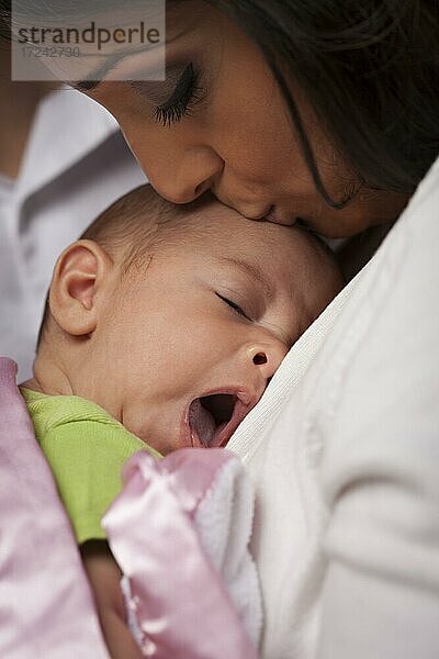 Junge attraktive ethnische Frau hält ihr gähnendes neugeborenes Baby