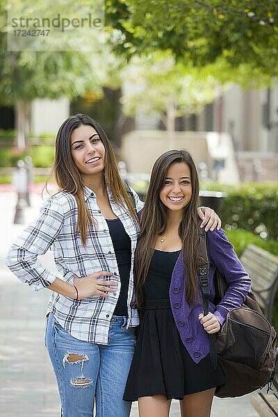 Porträt von zwei attraktiven multiethnischen Studentinnen  tragen Rucksack auf dem Schulcampus