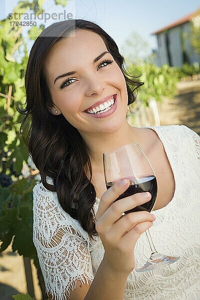 Hübsche multiethnische junge Frau genießt ein Glas Wein im Weinberg