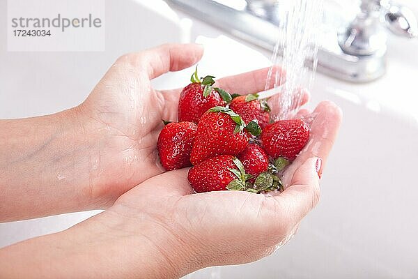 Frau wäscht Erdbeeren in der Küchenspüle
