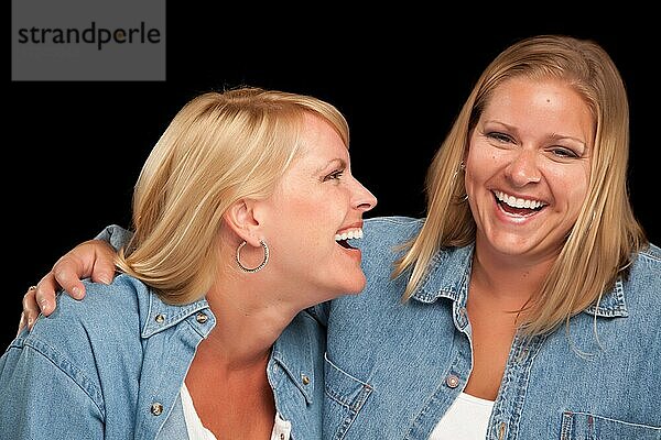 Zwei schöne Schwestern lachen vor einem schwarzen Hintergrund
