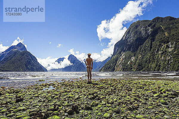 Neuseeland  Südinsel  Rückansicht eines nackten Mannes mit Blick auf das fließende Wasser des Milford Sound