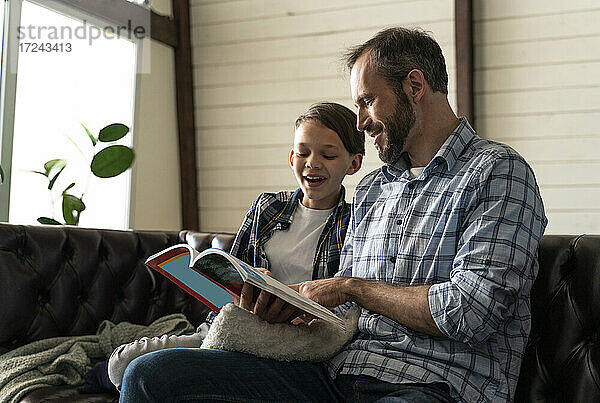 Vater und Sohn lesen ein Buch  während sie zu Hause sitzen