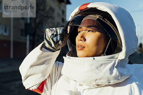 Weibliche Astronautin schaut weg  während sie bei Sonnenuntergang ihren Helm öffnet
