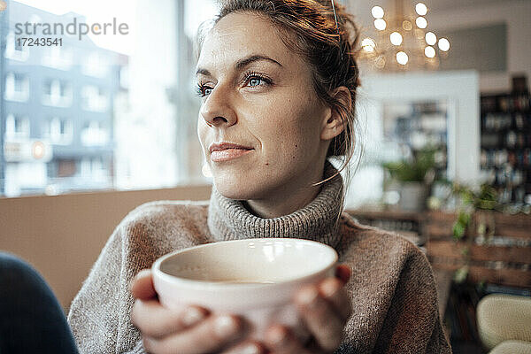 Mittlere erwachsene Frau mit Kaffee nachdenklich  während sie im Café wegschaut
