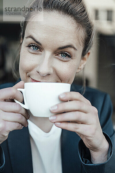 Mittlere erwachsene Geschäftsfrau trinkt Kaffee in einem Cafe