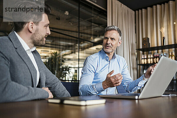 Männliche Unternehmer mit Laptop bei der Strategieplanung im Sitzungssaal des Büros