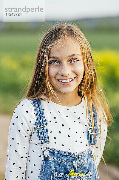 Lächelndes blondes Mädchen auf einem landwirtschaftlichen Feld