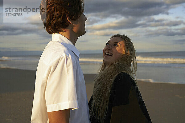 Lächelndes Paar am Strand bei Sonnenuntergang
