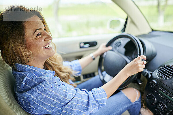 Glückliche Frau schaut beim Autofahren weg