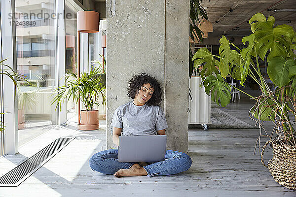 Müde Frau mit Laptop sitzt auf dem Boden zu Hause Wohnung
