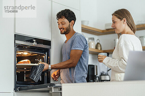 Mann mit Freundin bei der Zubereitung von Croissants in der Küche zu Hause