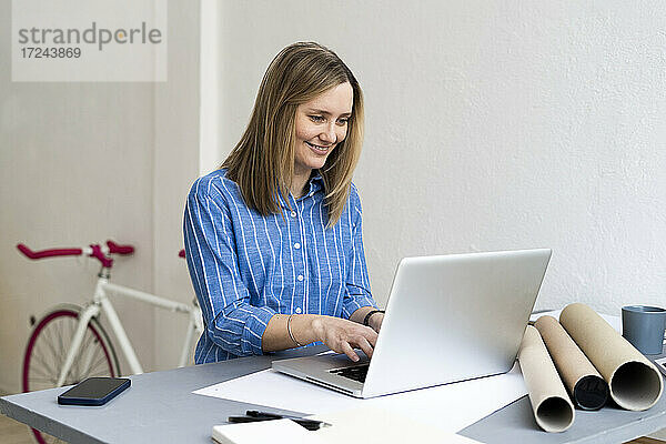 Lächelnde Geschäftsfrau bei der Arbeit am Schreibtisch im Büro