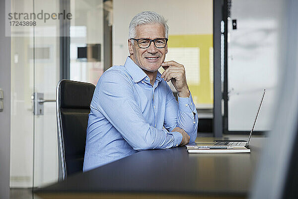 Lächelnder Geschäftsmann mit Brille im Büro