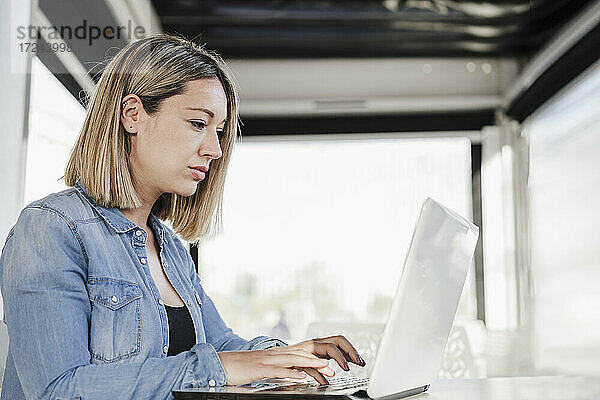 Schöne Geschäftsfrau  die einen Laptop benutzt und in einem Café sitzt