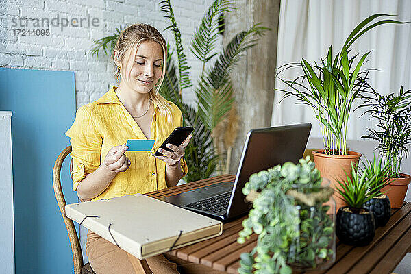 Weibliche Fachkraft bei der Online-Zahlung per Kreditkarte  während sie zu Hause im Büro sitzt
