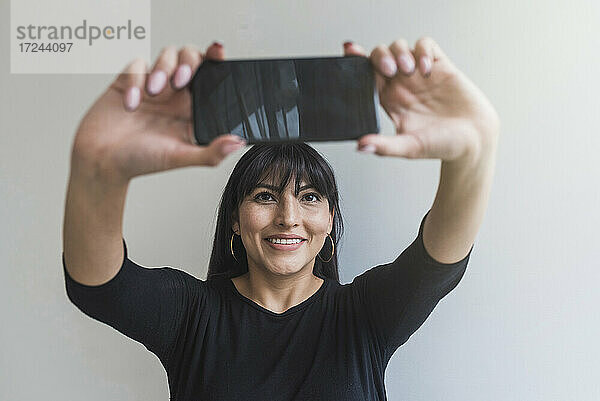 Mittlere erwachsene Frau  die zu Hause ein Selfie mit ihrem Smartphone macht